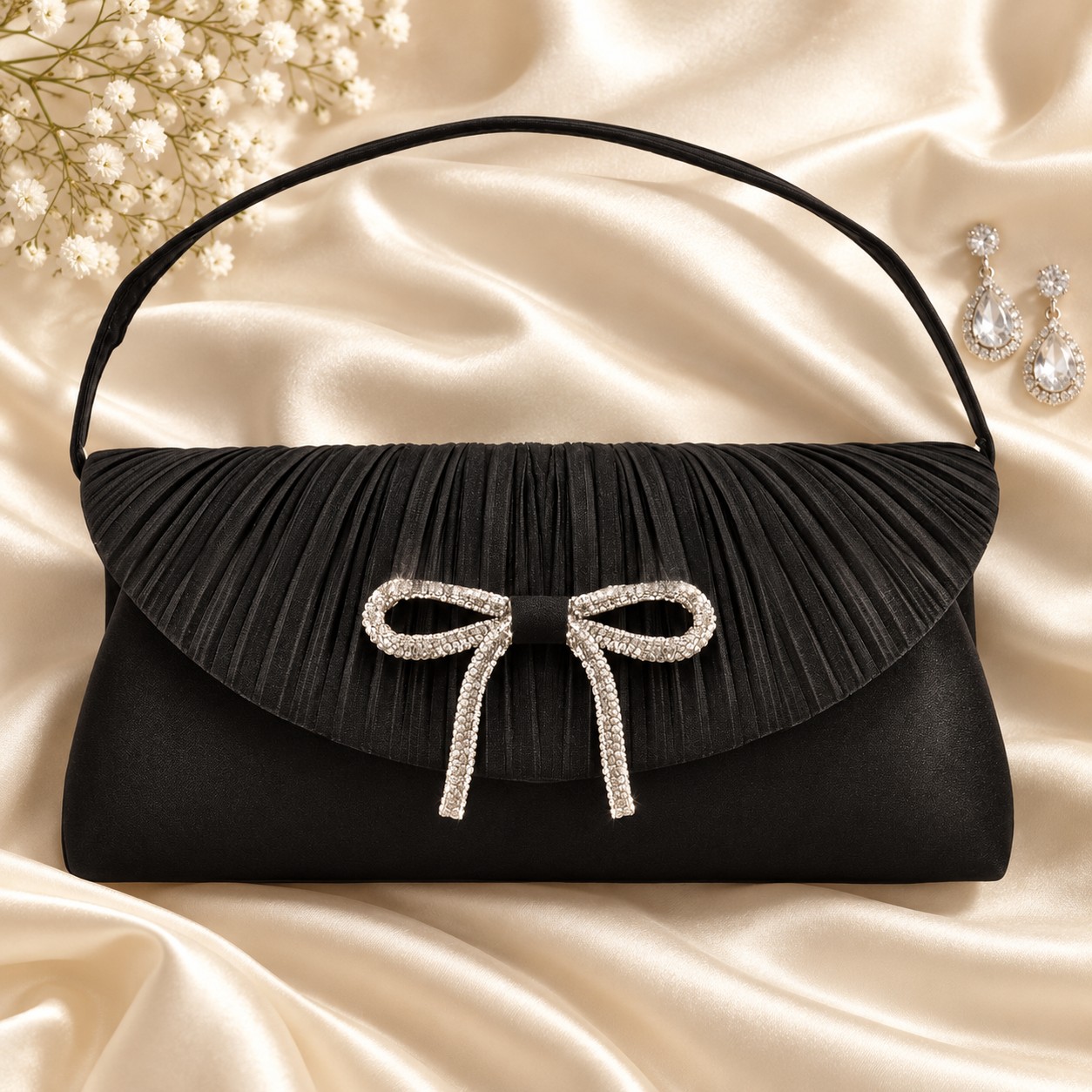 Black pleated satin bow clutch styled on ivory silk